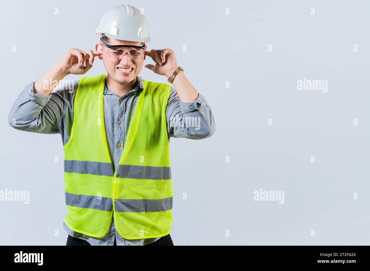 Young engineer covering ears isolated. Engineer man with ear pain. Concept of engineer covering his ears with pain expression Stock Photo