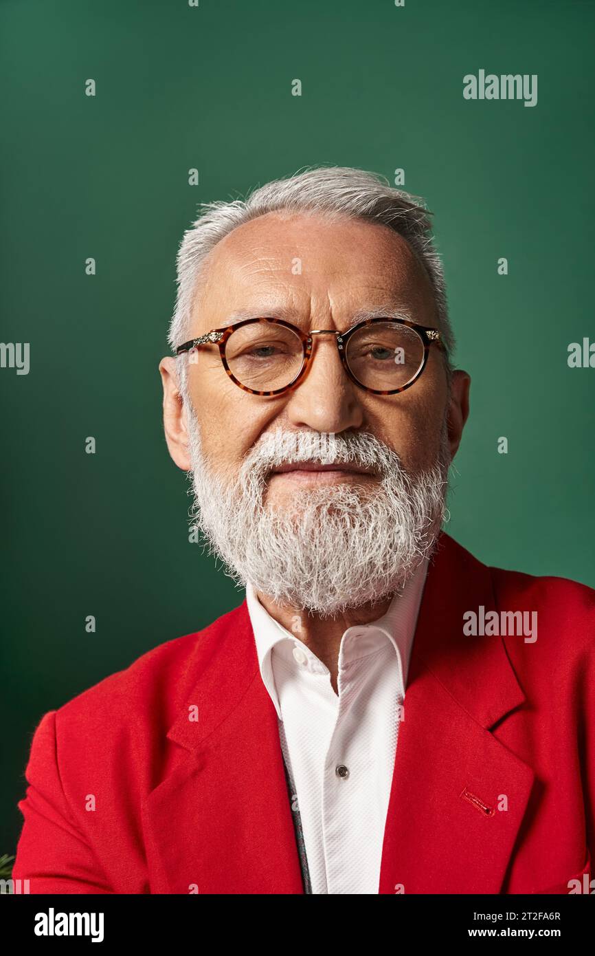 portrait of elegant Santa in glasses with white beard and looking at camera, winter concept Stock Photo
