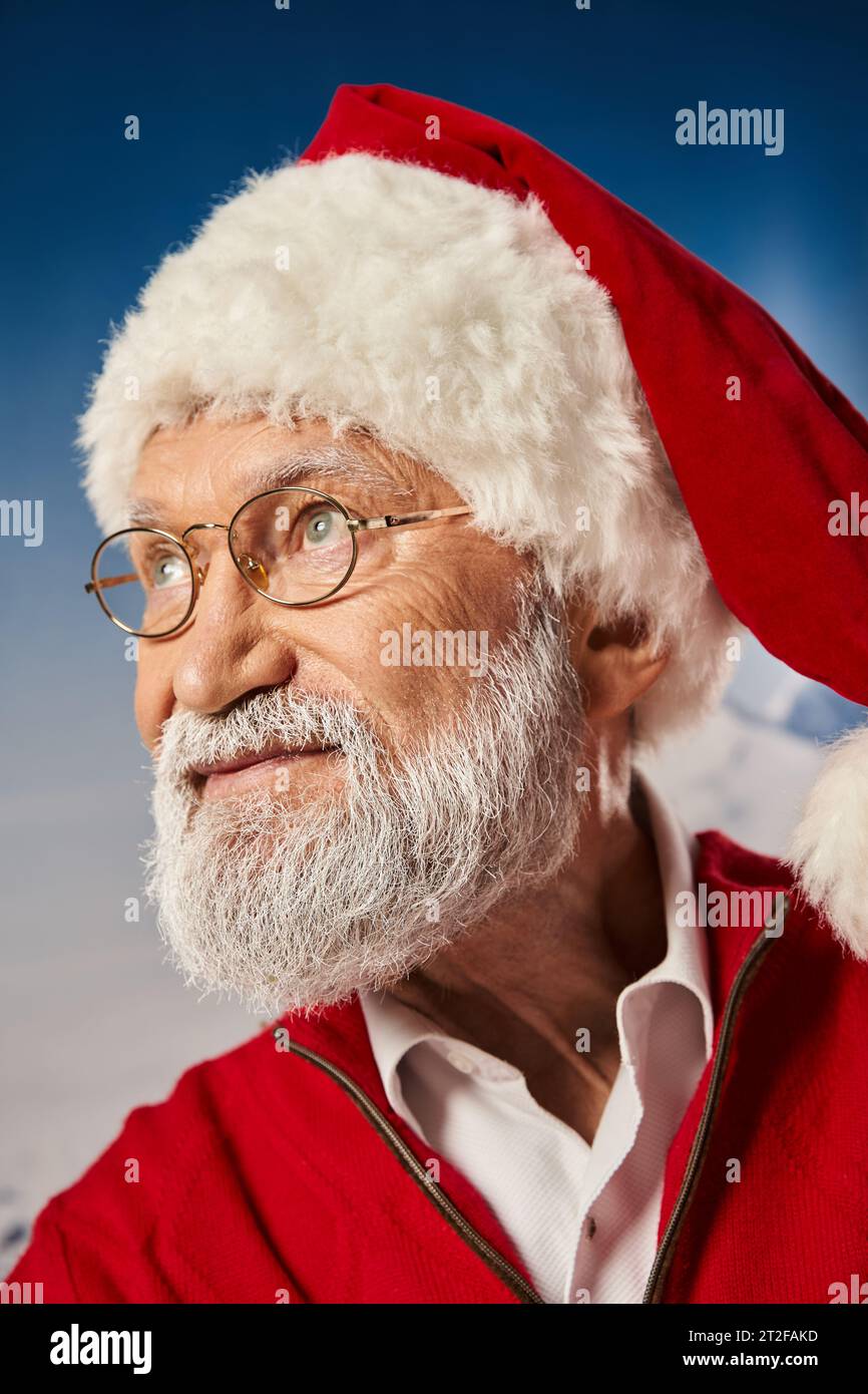 white bearded old man in Santa festive costume wearing glasses and looking away, winter concept Stock Photo
