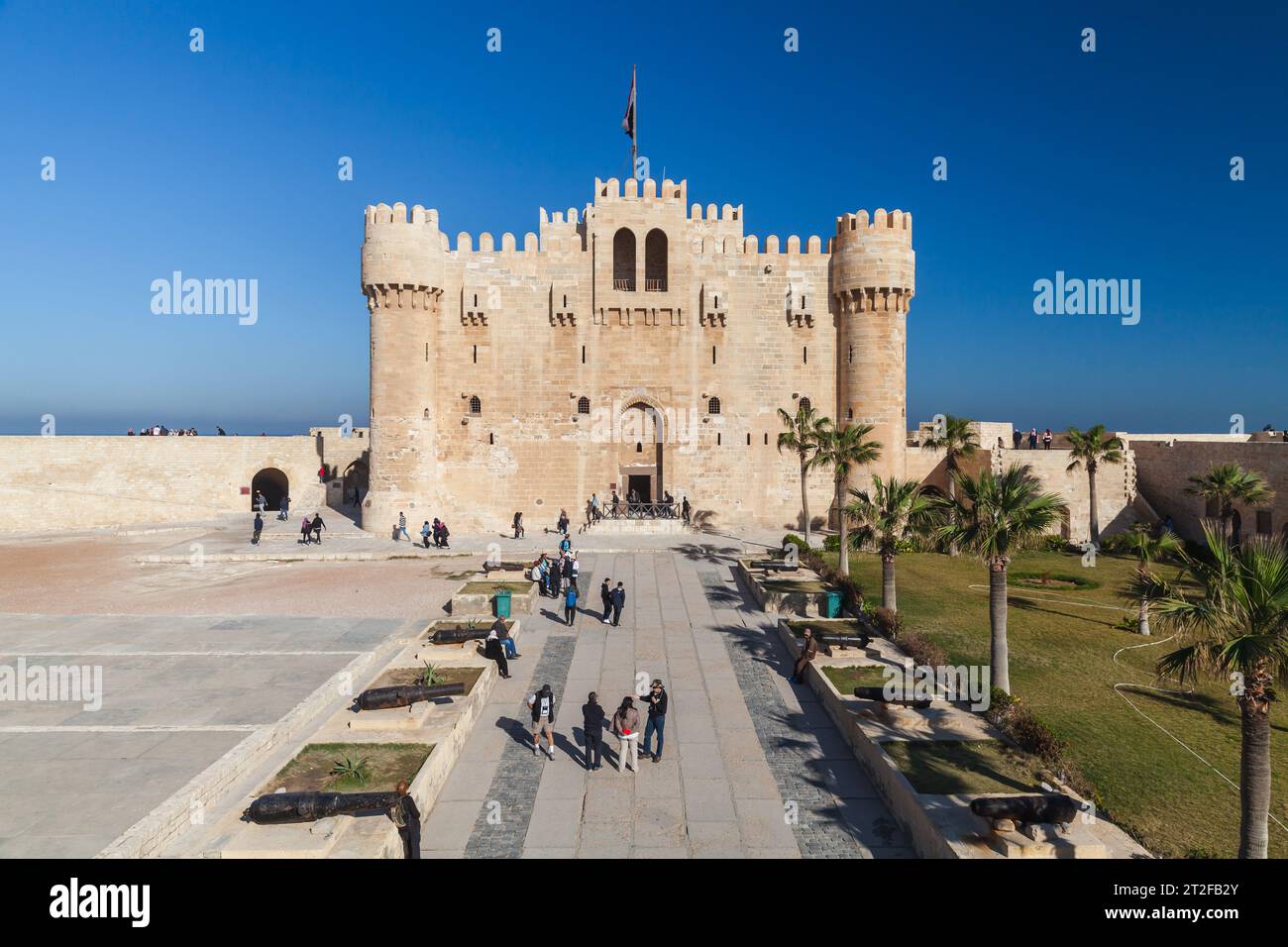 Alexandria, Egypt - December 14, 2018: People walk in front of The Citadel of Qaitbay or the Fort of Qaitbay. It is a 15th-century defensive fortress Stock Photo