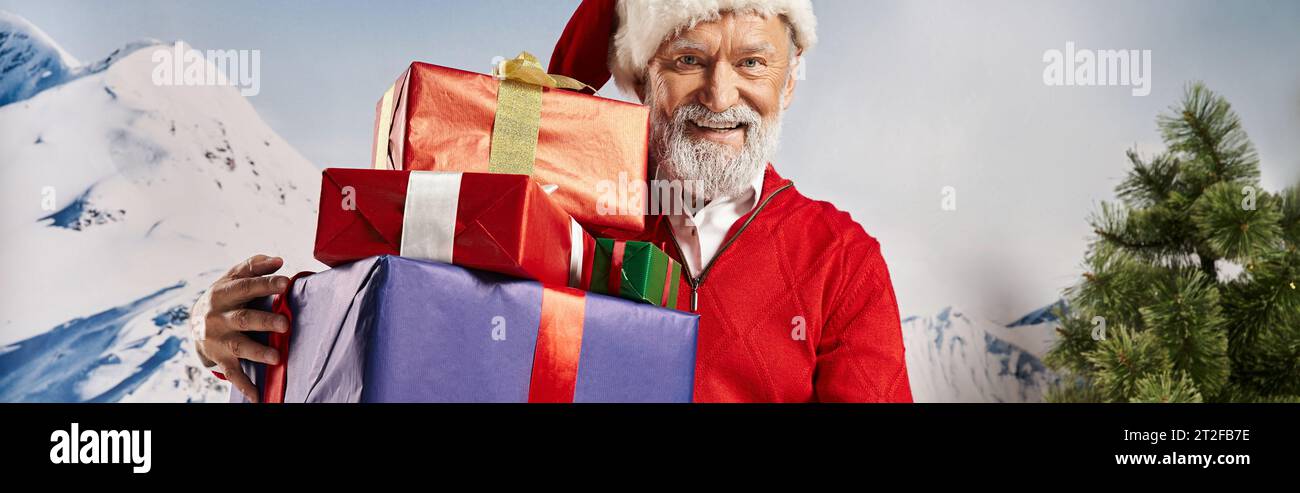 cheerful man in Santa costume with white beard showing presents at camera, winter concept, banner Stock Photo
