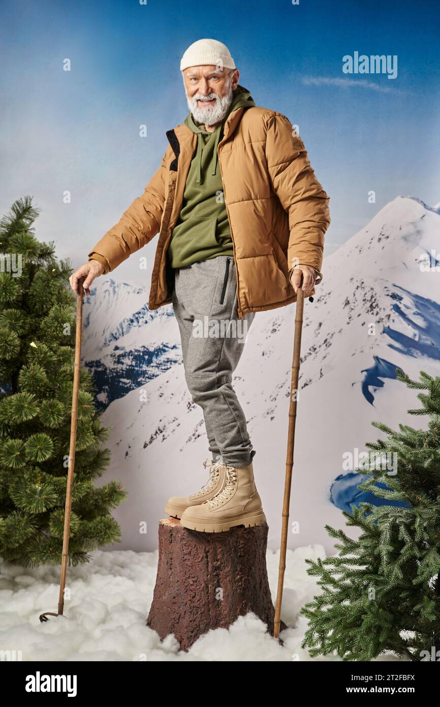 athletic man standing on tree stump and holding ski poles smiling at camera, winter concept Stock Photo