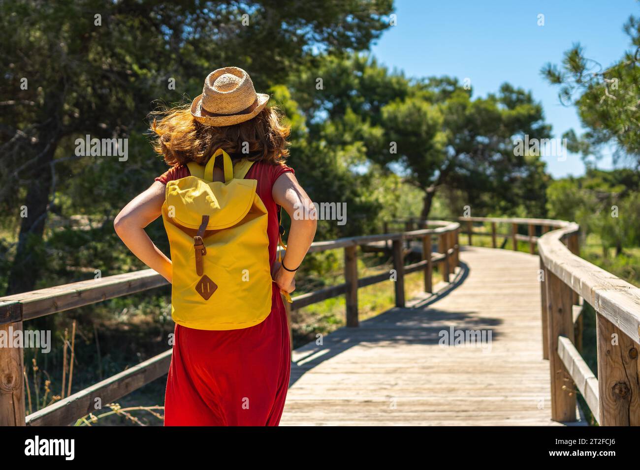 A young tourist woman walking along the wooden walkway towards Moncayo Beach in Guardamar del Segura, Alicante. Community of Valencia. Spain Stock Photo