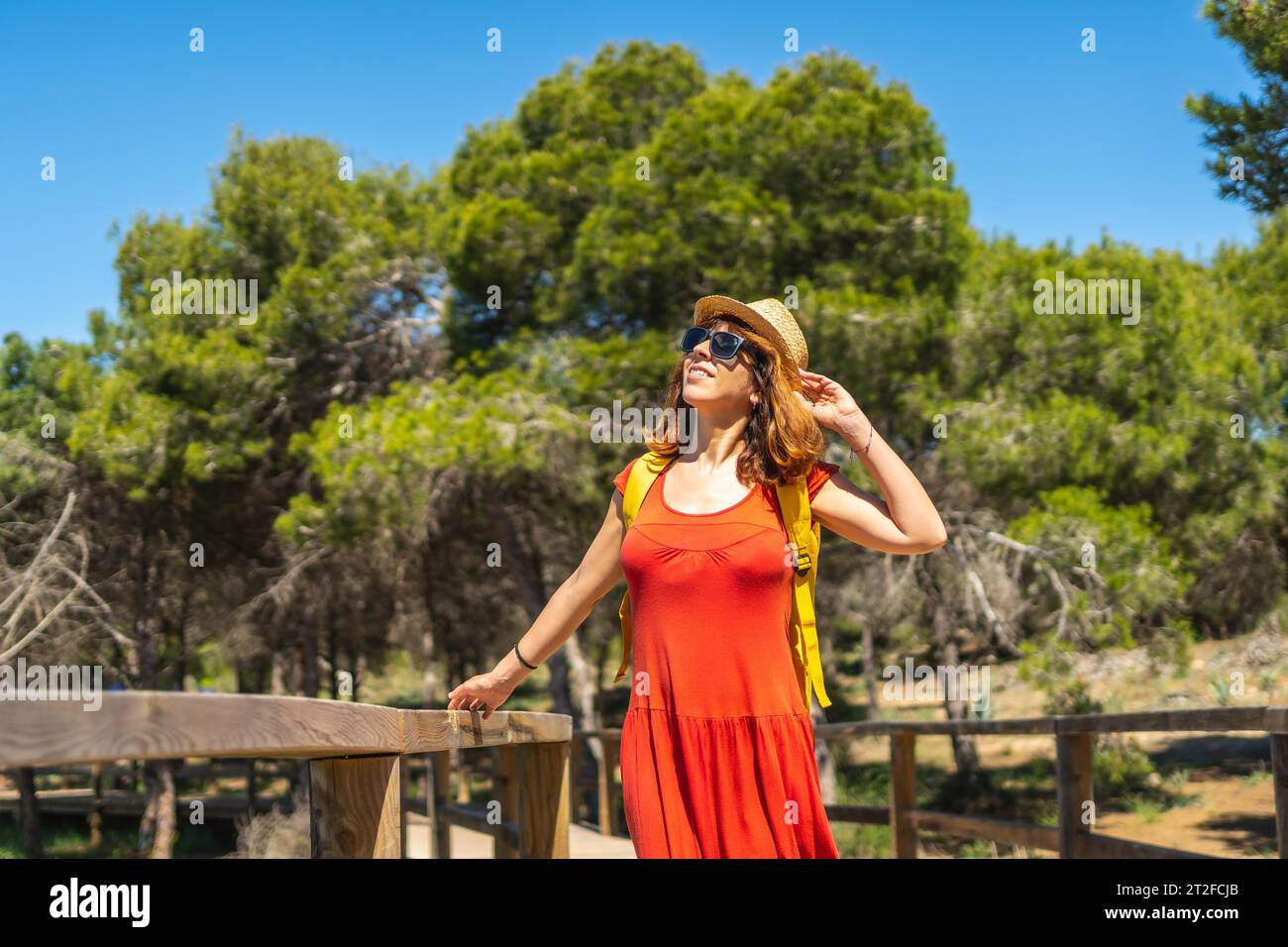 A young woman in a red dress on the path to the Moncayo Beach of the Mediterranean Sea in Guardamar del Segura, Alicante. Community of Valencia. Spain Stock Photo