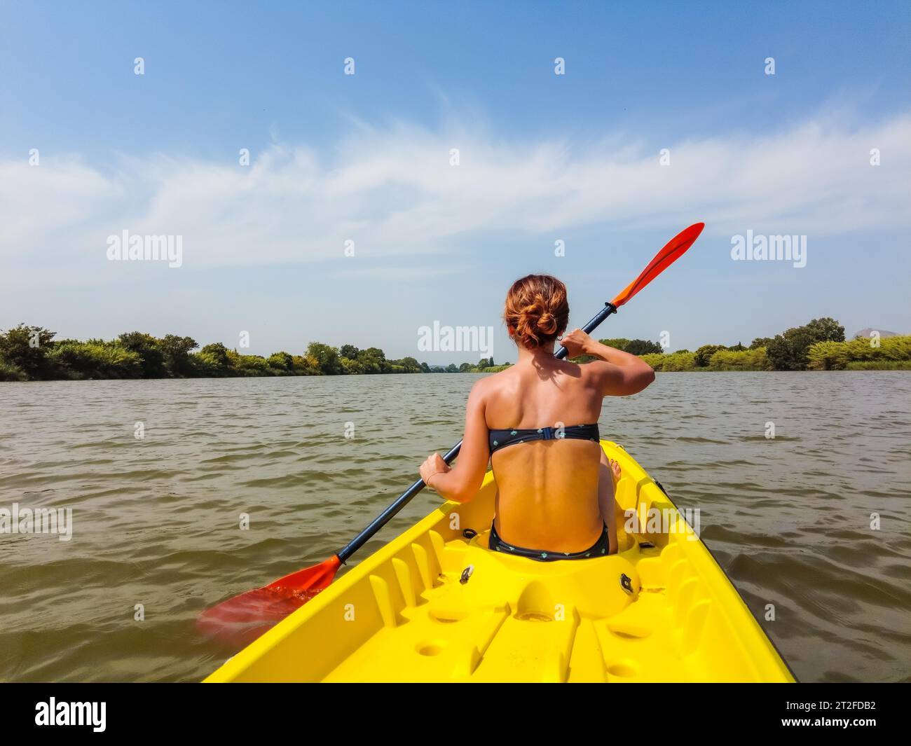 A young woman in the canoe canoeing in a natural park in Catalonia, a river next to the beach in Estartit Stock Photo