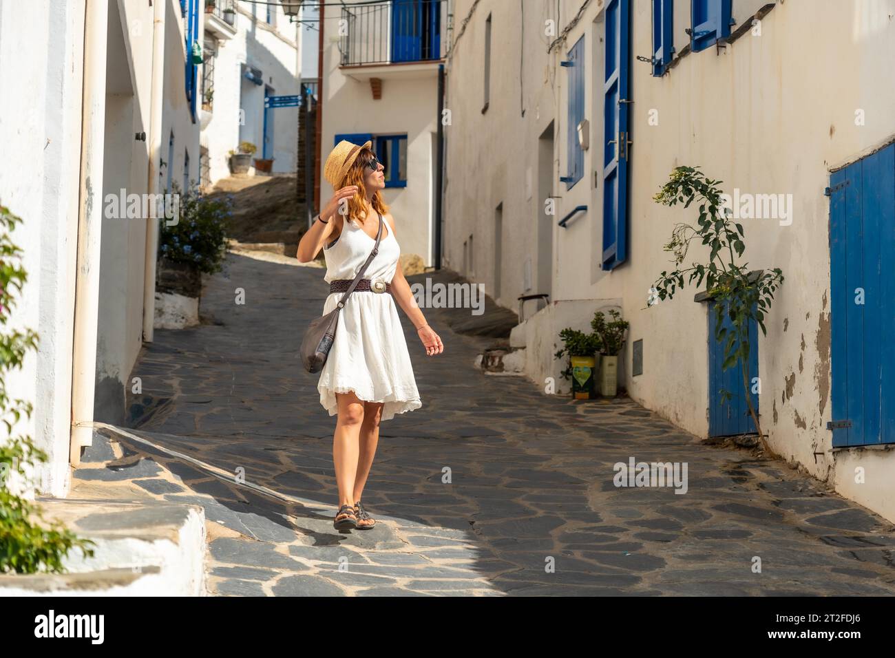 A young tourist with a hat walking through the streets of Cadaques town on the Costa Brava of Catalonia, Gerona, Mediterranean Sea. Spain Stock Photo