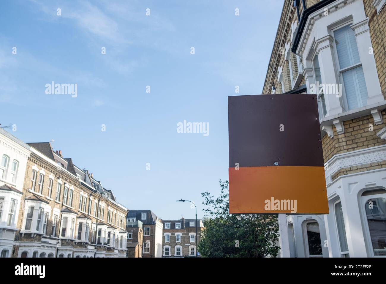 Blank estate agent sign on street of urban terraced houses with copy space Stock Photo