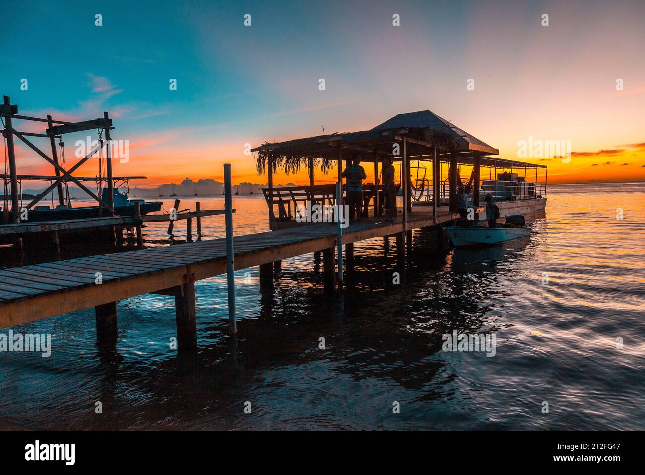 A pier and the boat in the background on a beach on Roatan Island ...