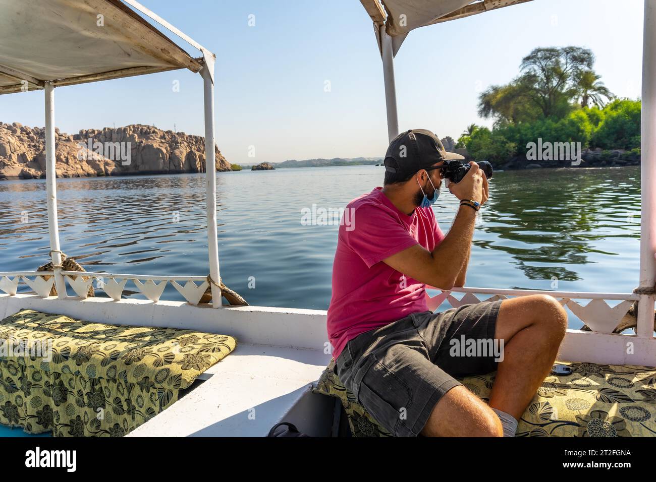 A young man on the boat that takes you to the Temple of Philae with its beautiful columns, a Greco-Roman construction on the River Nile, a temple Stock Photo