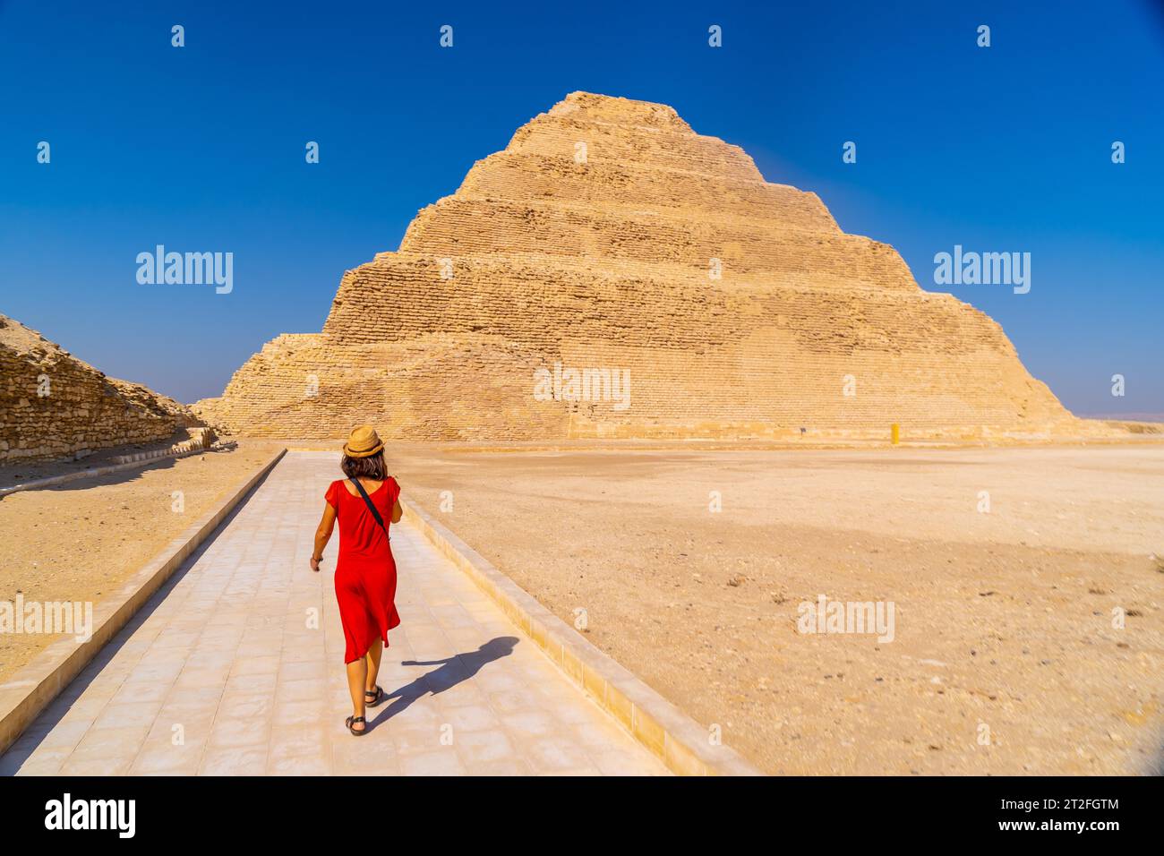 A young tourist in a red dress at the Stepped Pyramid of Djoser ...