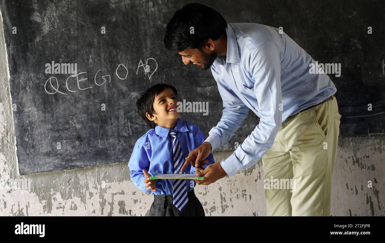 Indian teacher teaching to rural school student in classroom, Typical scene in a rural or small village school in India Stock Photo