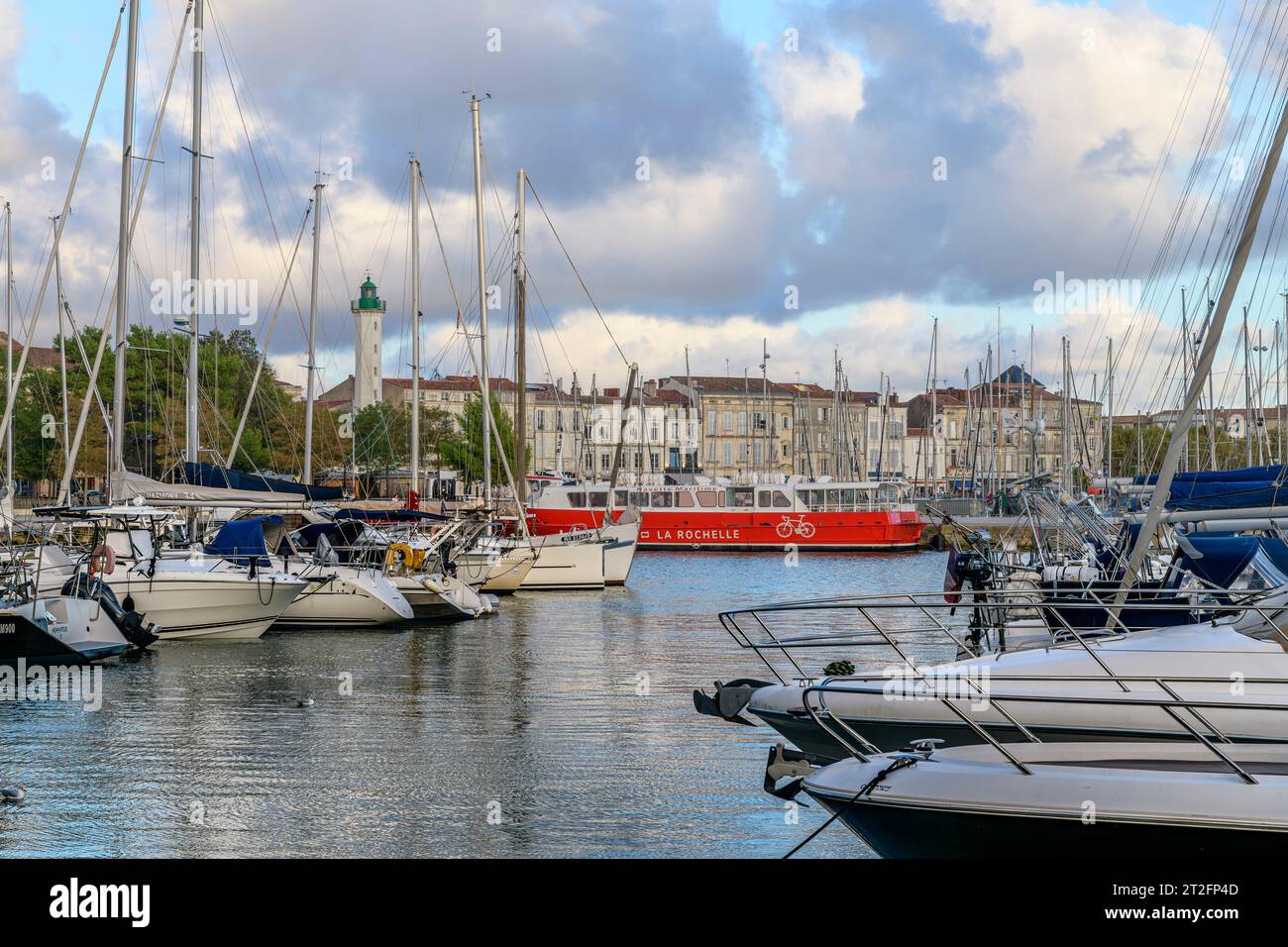 The red Ferry to l'île de Ré in evening light at the beautiful seaside town of La Rochelle on the west coast of France with yachts and fishing boats. Stock Photo