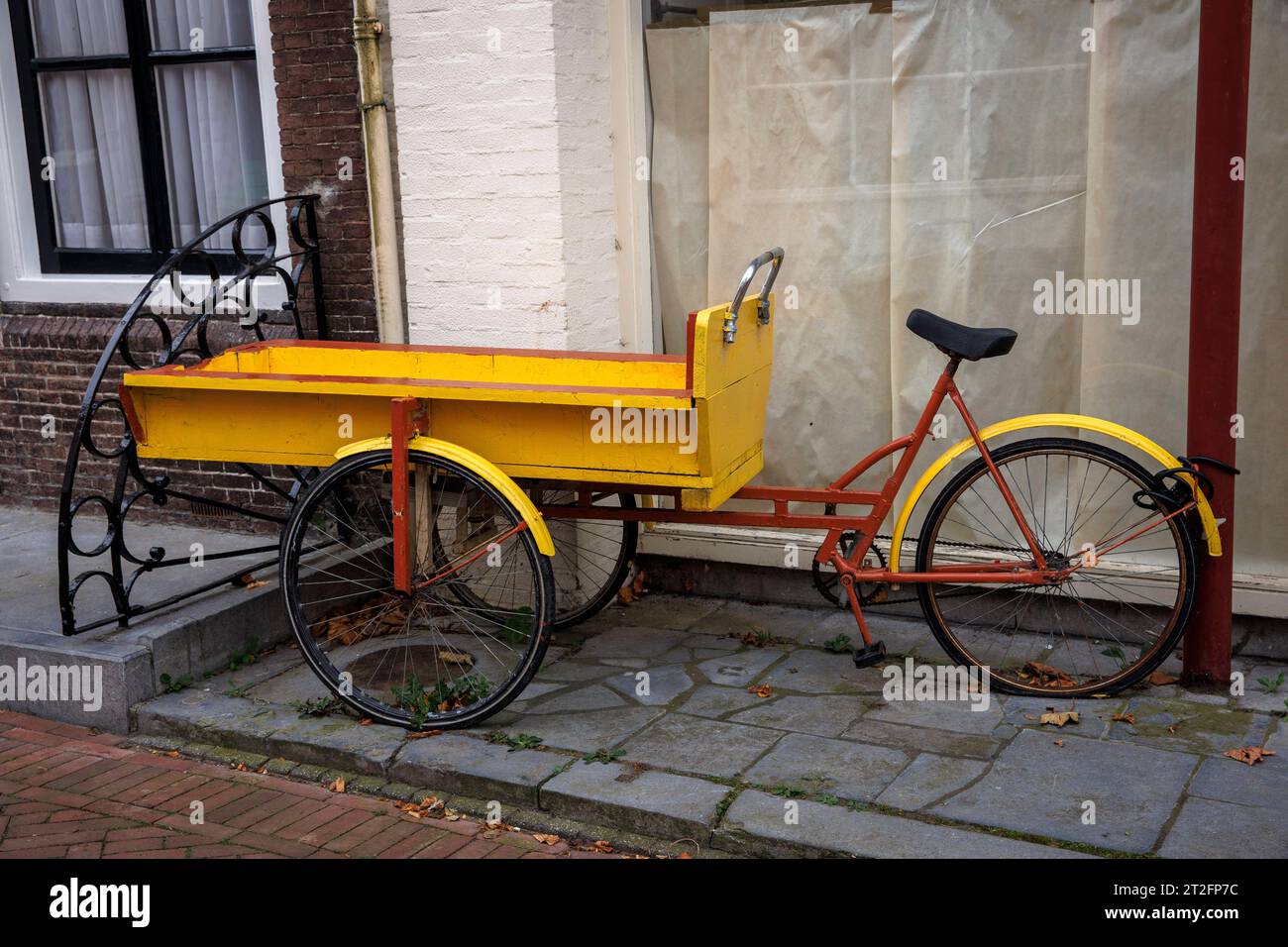 old cargo bike stands in front of a house in Zierikzee on the peninsula Schouwen-Duiveland, Zeeland, Netherlands. altes Lastenfahrrad steht vor einem Stock Photo