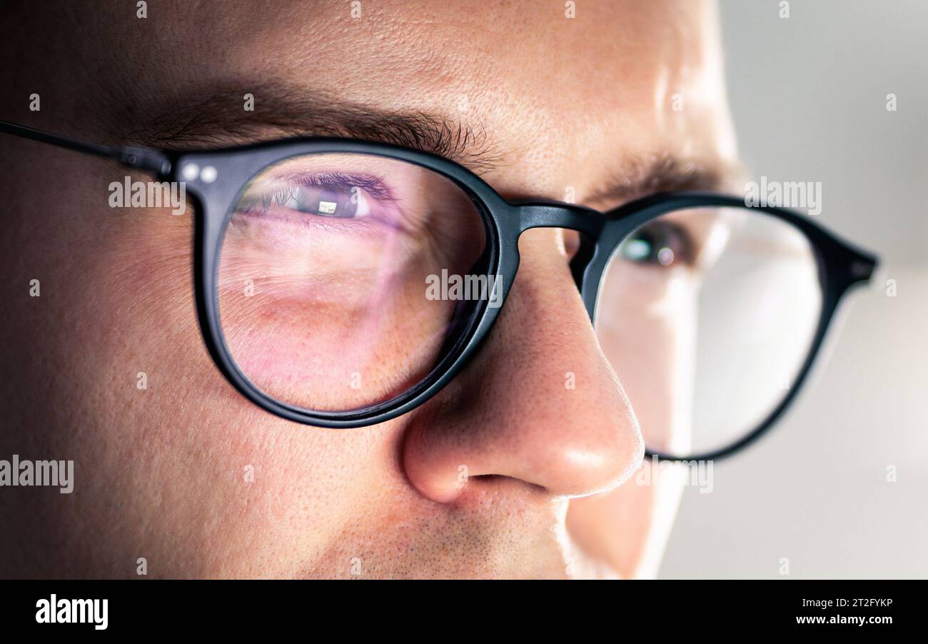 Glasses and eye. Looking at screen. Focus on work. Computer, laptop, phone or tv reflect. Tired squinting eyes. Serious man with poor eyesight. Stock Photo
