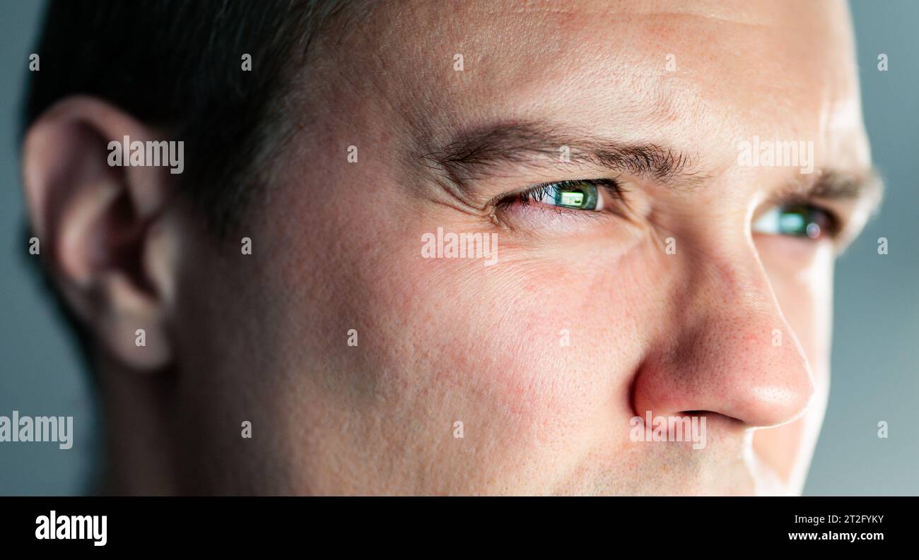 Squinting eyes of a man looking at screen. Poor eyesight, bad vision. Light from laptop computer or phone. Guy watching tv. Focus on work. Stock Photo