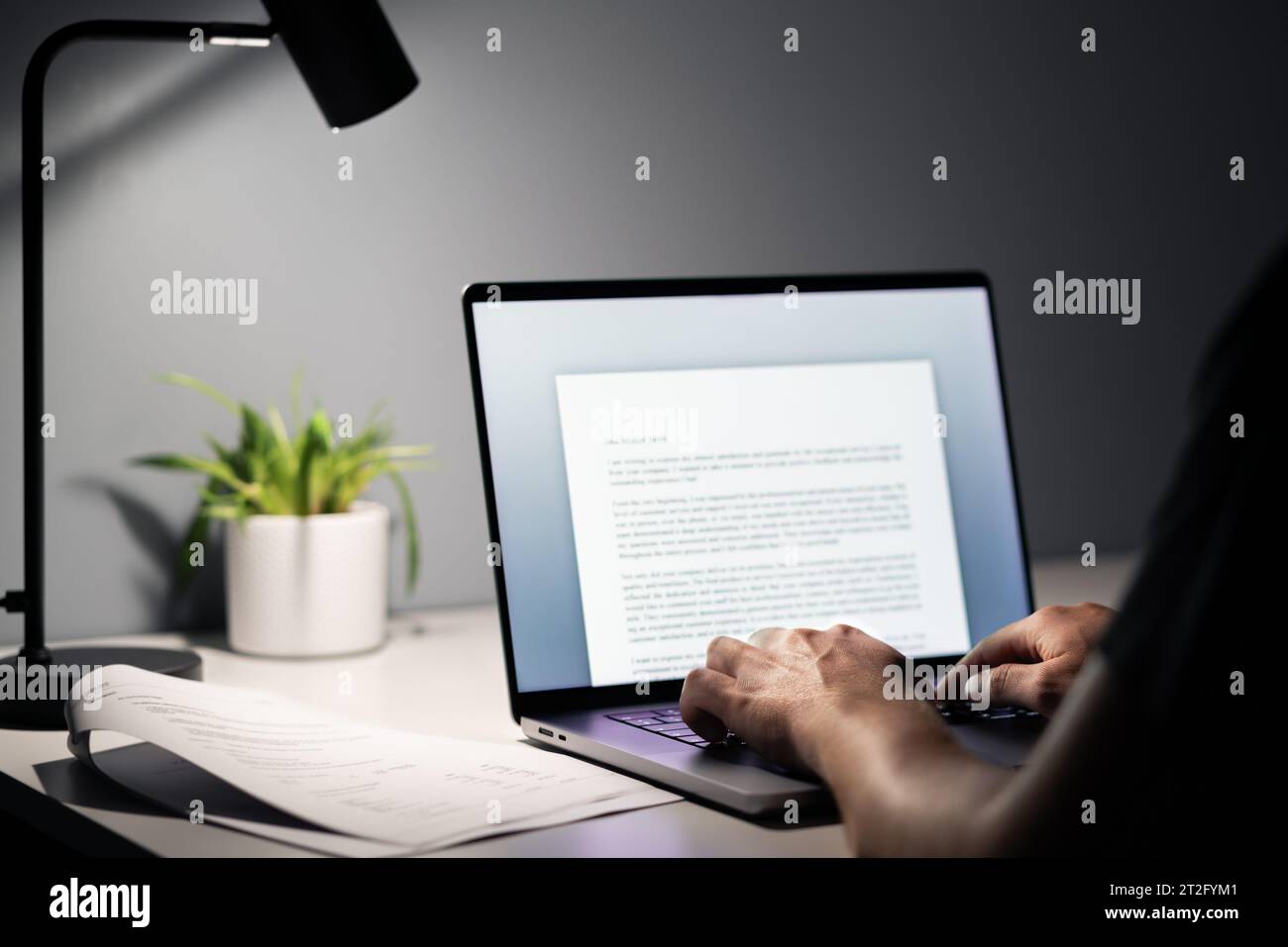 Man writing text document, essay or letter with laptop. Freelance writer, journalist or entrepreneur working late at night, overtime. Stock Photo