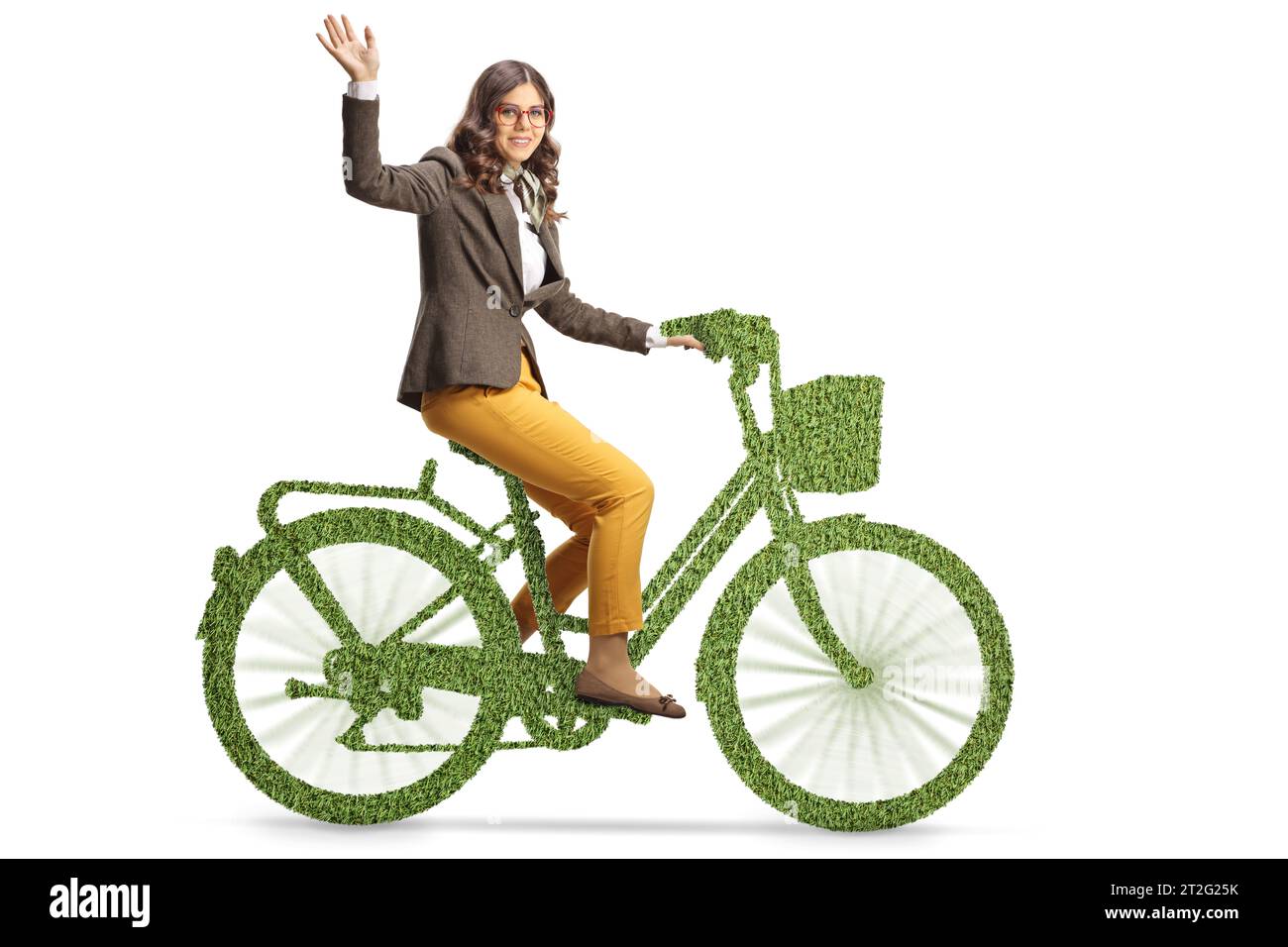 Young woman riding a bicycle made of grass and waving isolated on white background Stock Photo