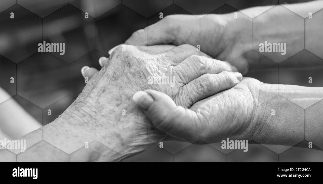 Hands of young woman holding the hands of an elderly person, geometric pattern Stock Photo