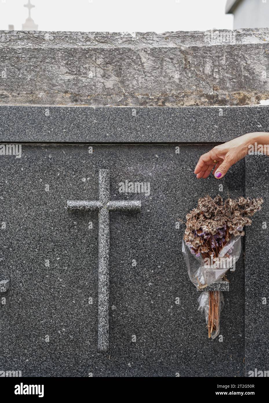 Paying your respects. A female hand placing flowers on a cemetery grave