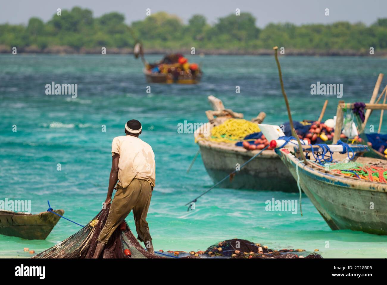 African fisherman catches fishing nets and looks out to sea, sunny day , Zanzibar, tanzania. Stock Photo