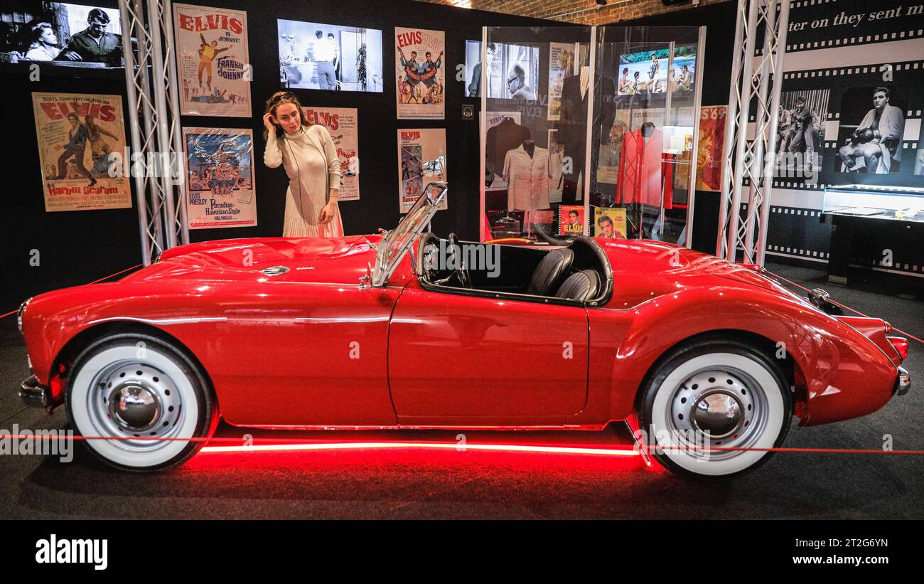 London, UK. 19th Oct, 2023. A visitor poses with Elvis' 1960 MGA 1600 MKI, the only one of Elvis' personal cars that ended up in one of his movies, used in the 1961 film 'Blue Hawaii'. The 'Direct from Graceland: Elvis' exhibition features over 400 artefacts and iconic belongings owned by Elvis, direct from the icon's Graceland home in Memphis, Tennessee. The exhibition opens on Oct 20 at the Arches London Bridge venue in Bermondsey Street. Credit: Imageplotter/Alamy Live News Stock Photo