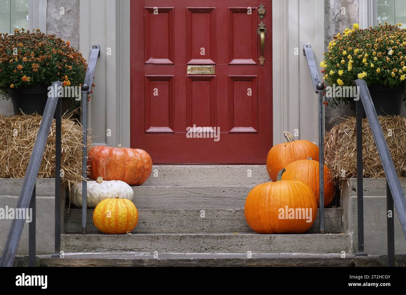 Front door with pumpkins and hay bale for fall or Thanksgiving decorations Stock Photo
