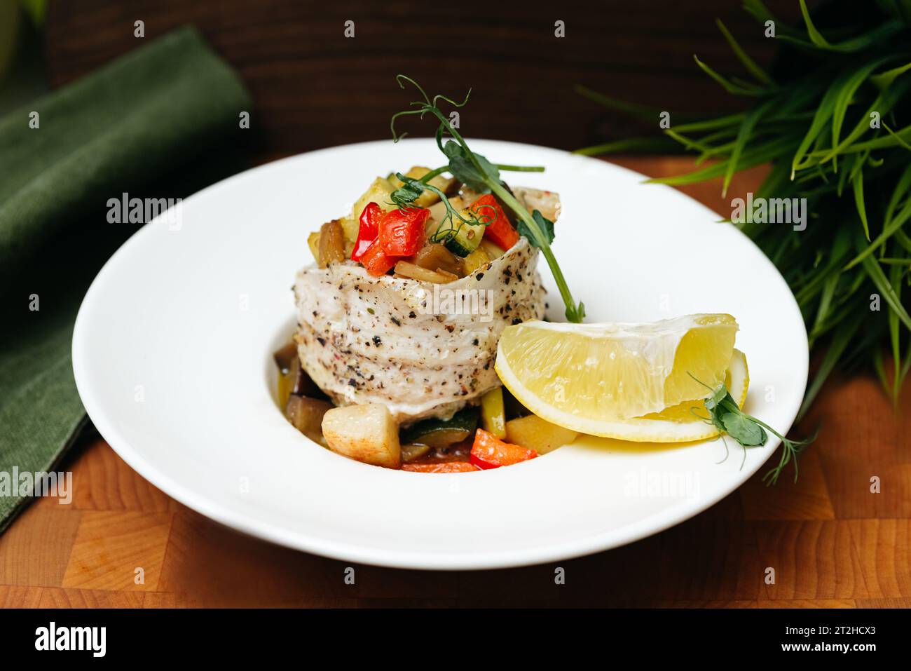 Baked sea bass with diced vegetables, red pepper, zucchini and micro