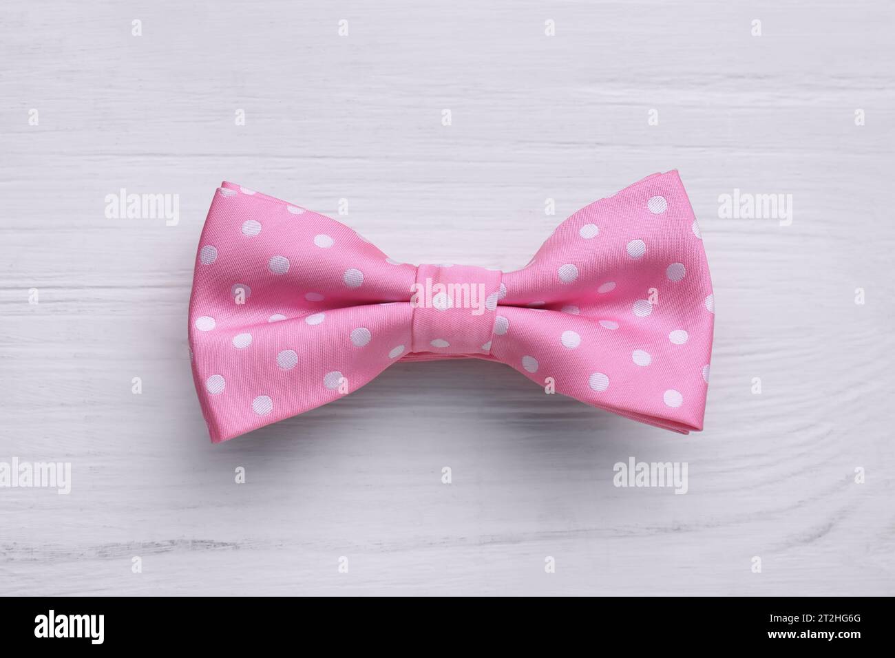 Stylish pink bow tie with polka dot pattern on white wooden table, top view Stock Photo