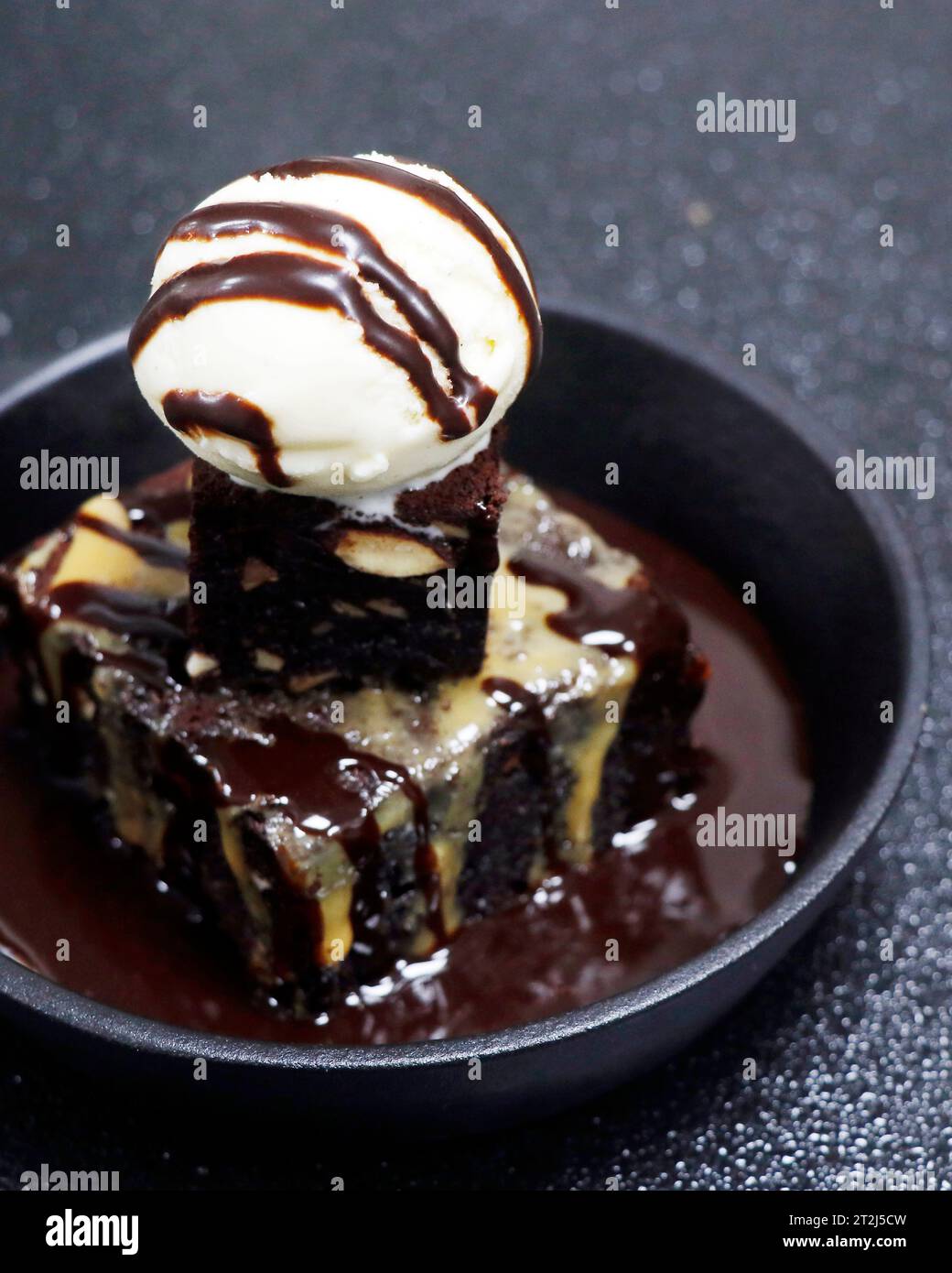 chocolate and walnut brownie cake with vanilla ice cream in black