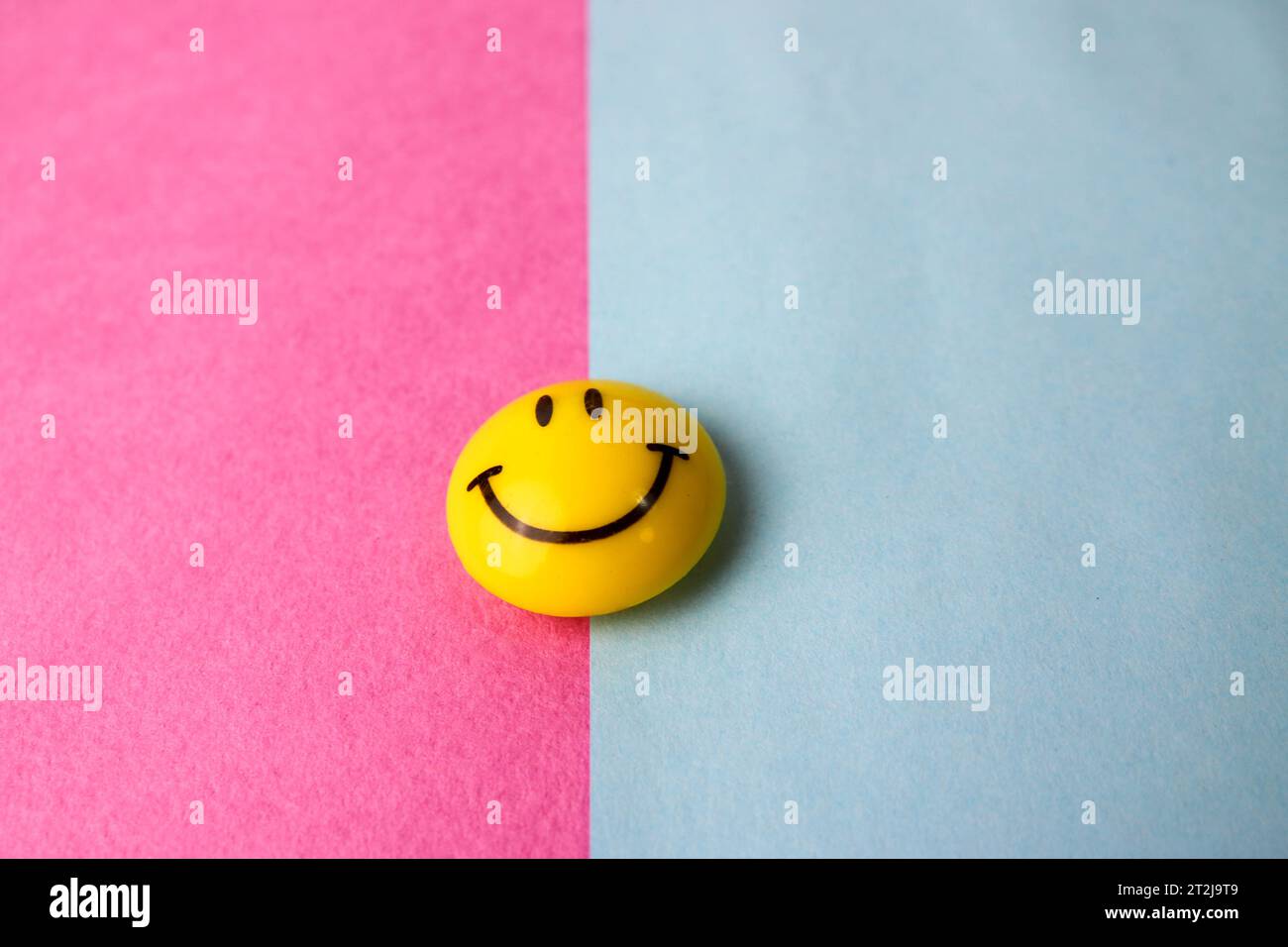 Round plastic yellow joyful smiling smiling toy round face Emoji on a pink blue violet background. Stock Photo