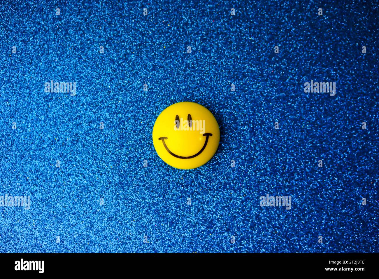 Round plastic yellow joyful smiling smiling toy round face Emoji on a blue background. Stock Photo