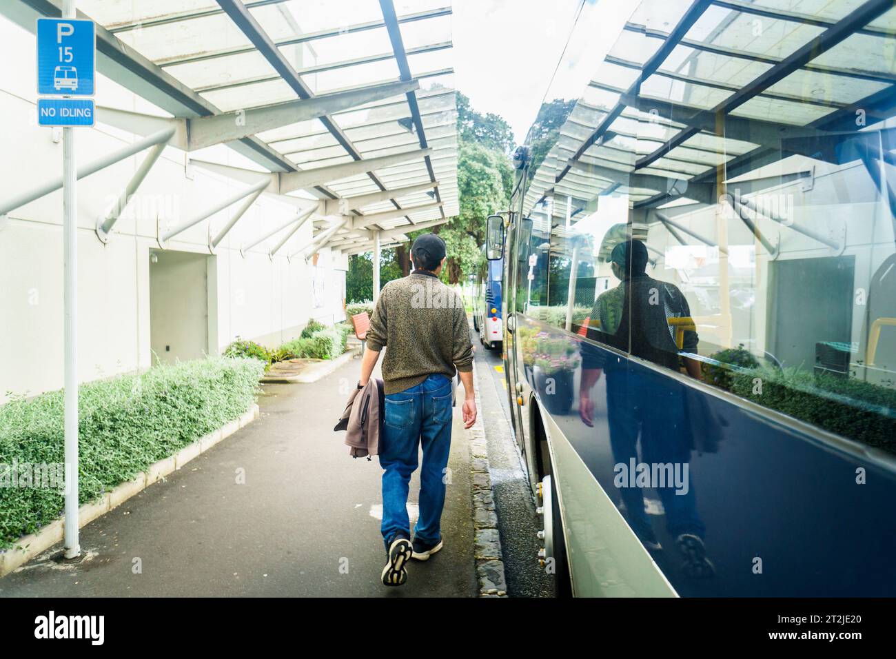 Man walking to the bus stop. No Idling 15 minutes bus parking sign on the side. Auckland. Stock Photo