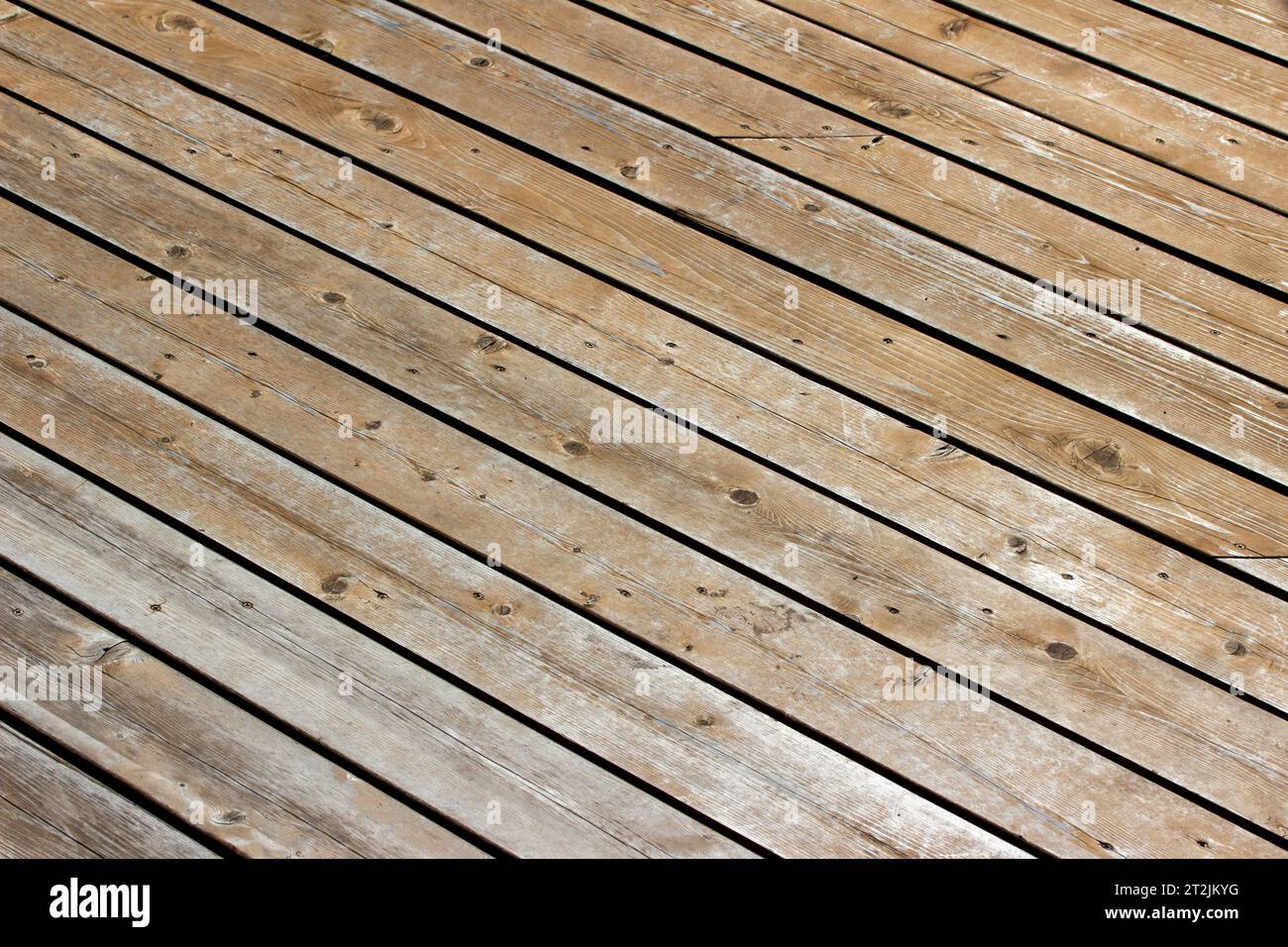 Full frame abstract macro texture background of a scuffed up diagonal pattern cedar deck flor in bright sunlight Stock Photo