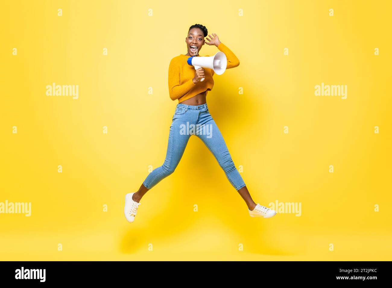 Portrait of cheerful young African American woman holding megaphone ...