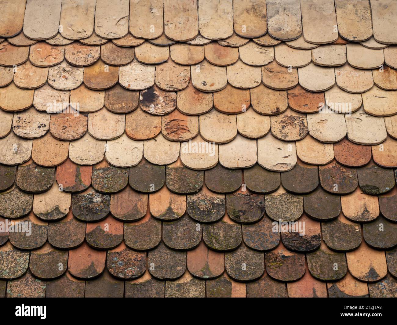 Old vintage style mossy weathered clay tile terracotta roof closeup Stock Photo