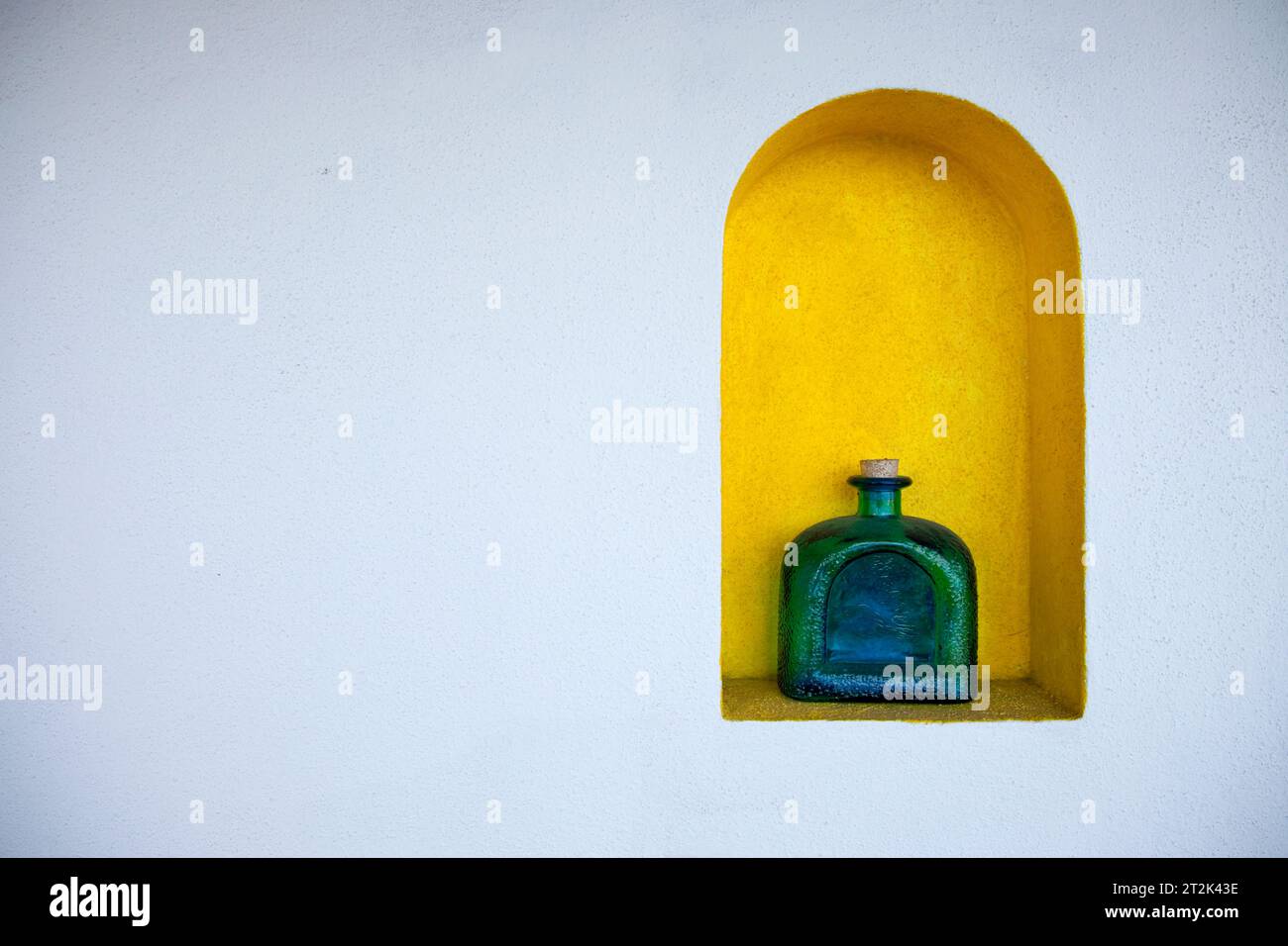 A Tequila bottle in a yellow nook on a white wall. Stock Photo