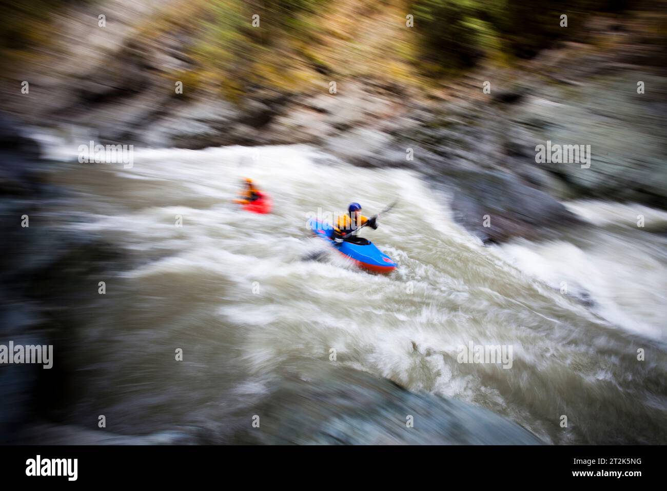 A whitewater kayaker battles fast moving water through a dangerous rapid. Stock Photo