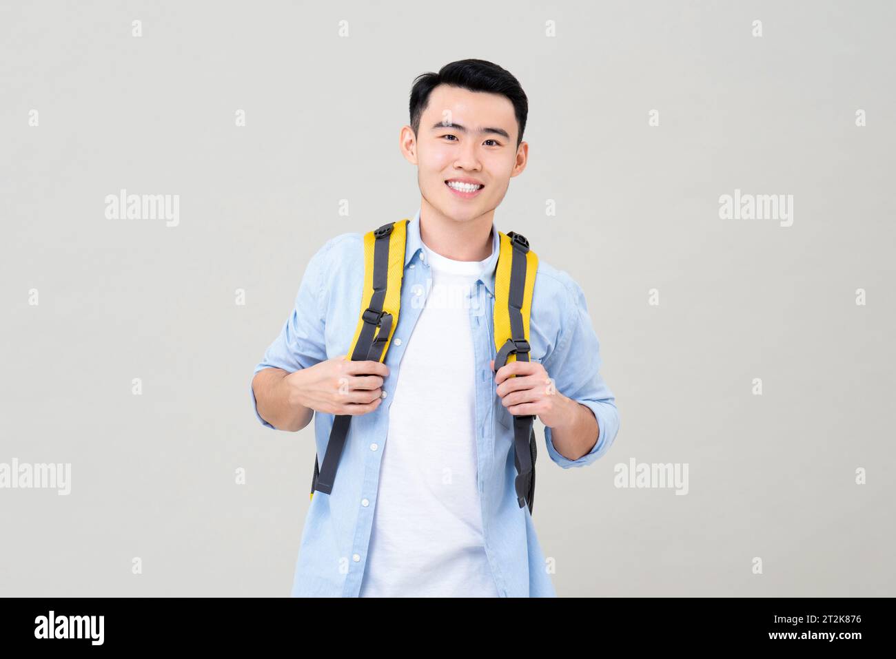 Porttrait of young smiling Asian tourist man with backpack studio shot isolated in gray background Stock Photo