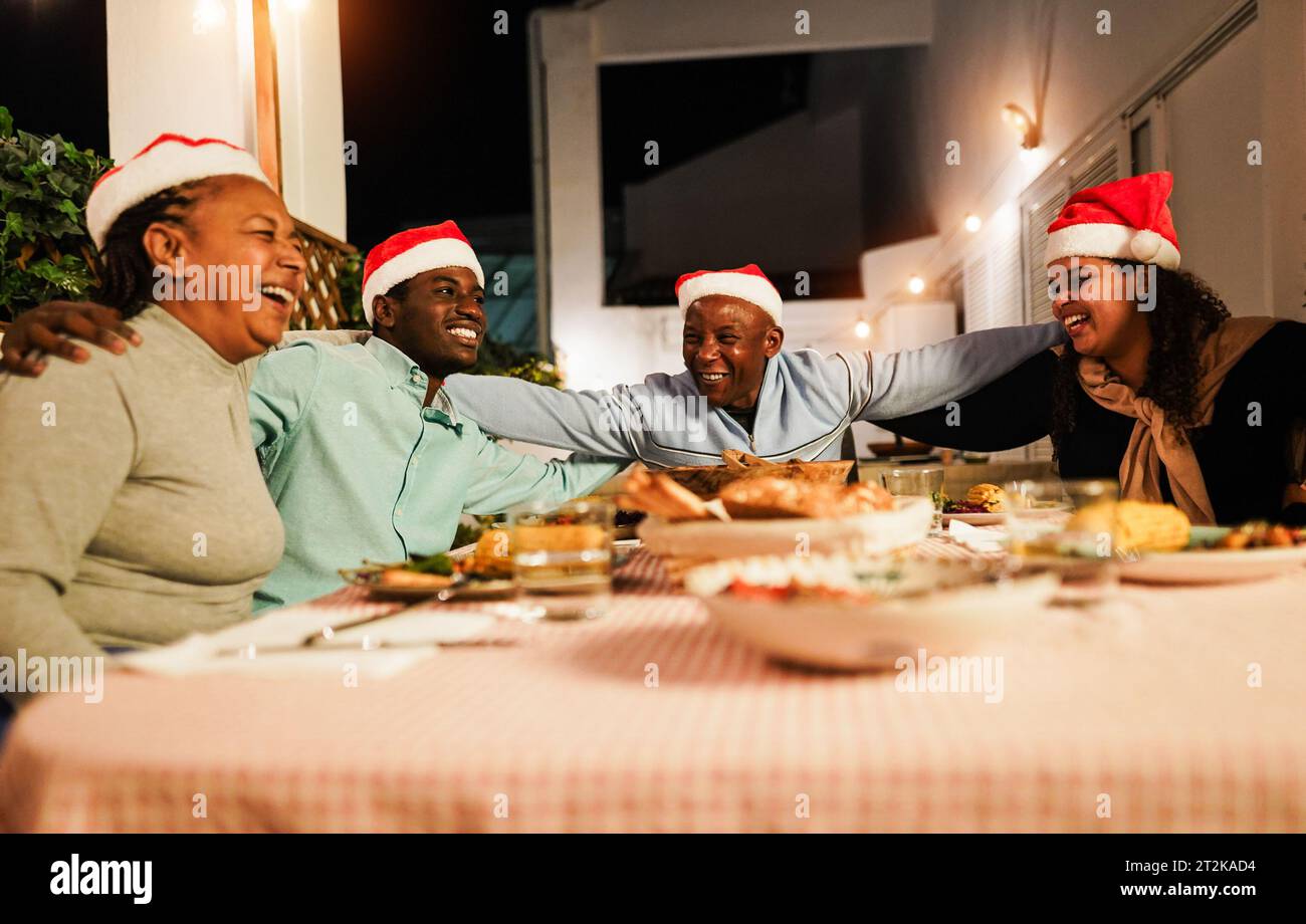 Happy african family having fun eating together during Christmas time - Holiday concept - Main focus on father face Stock Photo