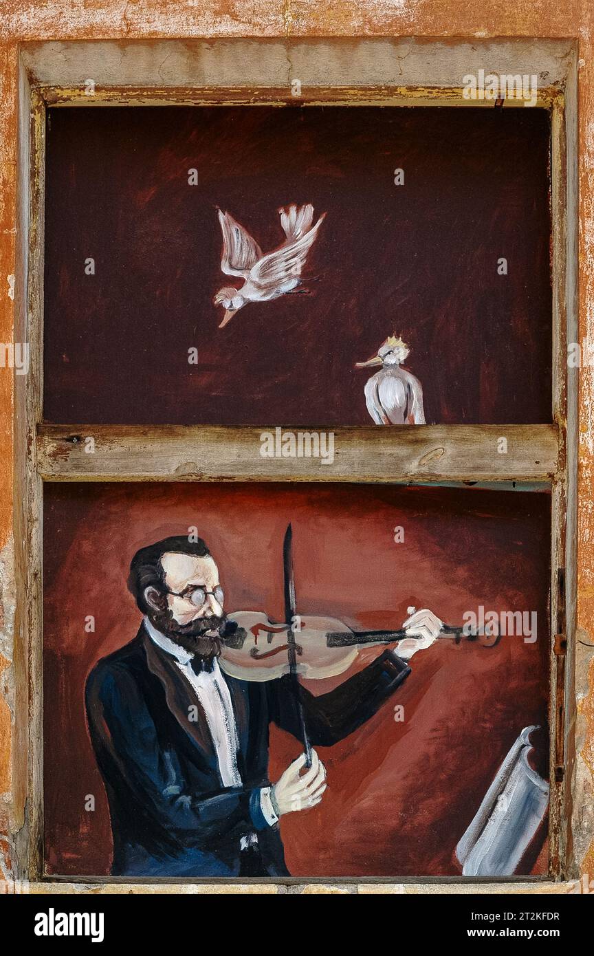 Bespectacled musician in jacket and bow tie plays a violin.  Street art on exterior of building in historic centre of Písek, South Bohemia, Czechia. Stock Photo