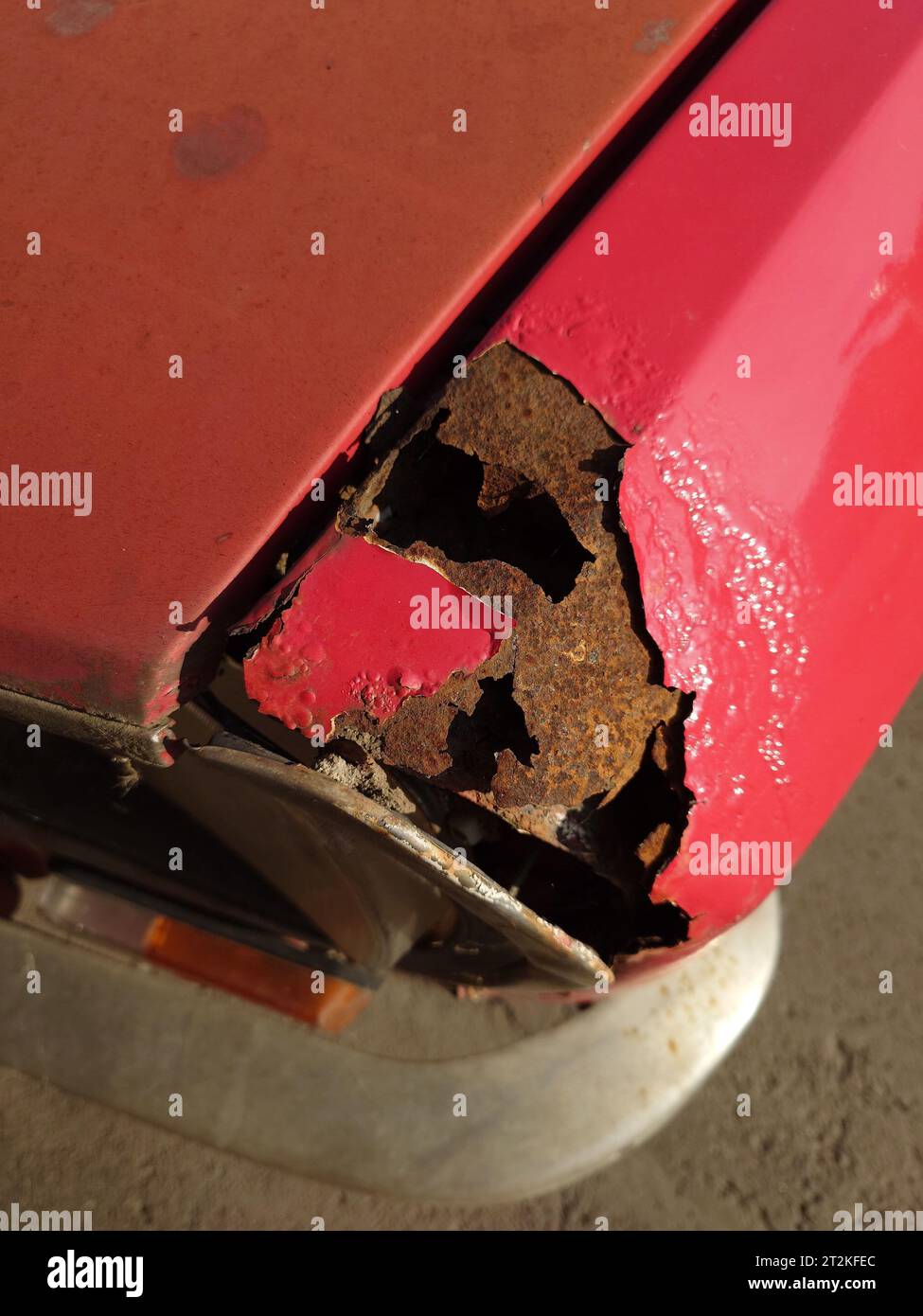 Completeley rusted through old car fender body panel. Red pain, top
