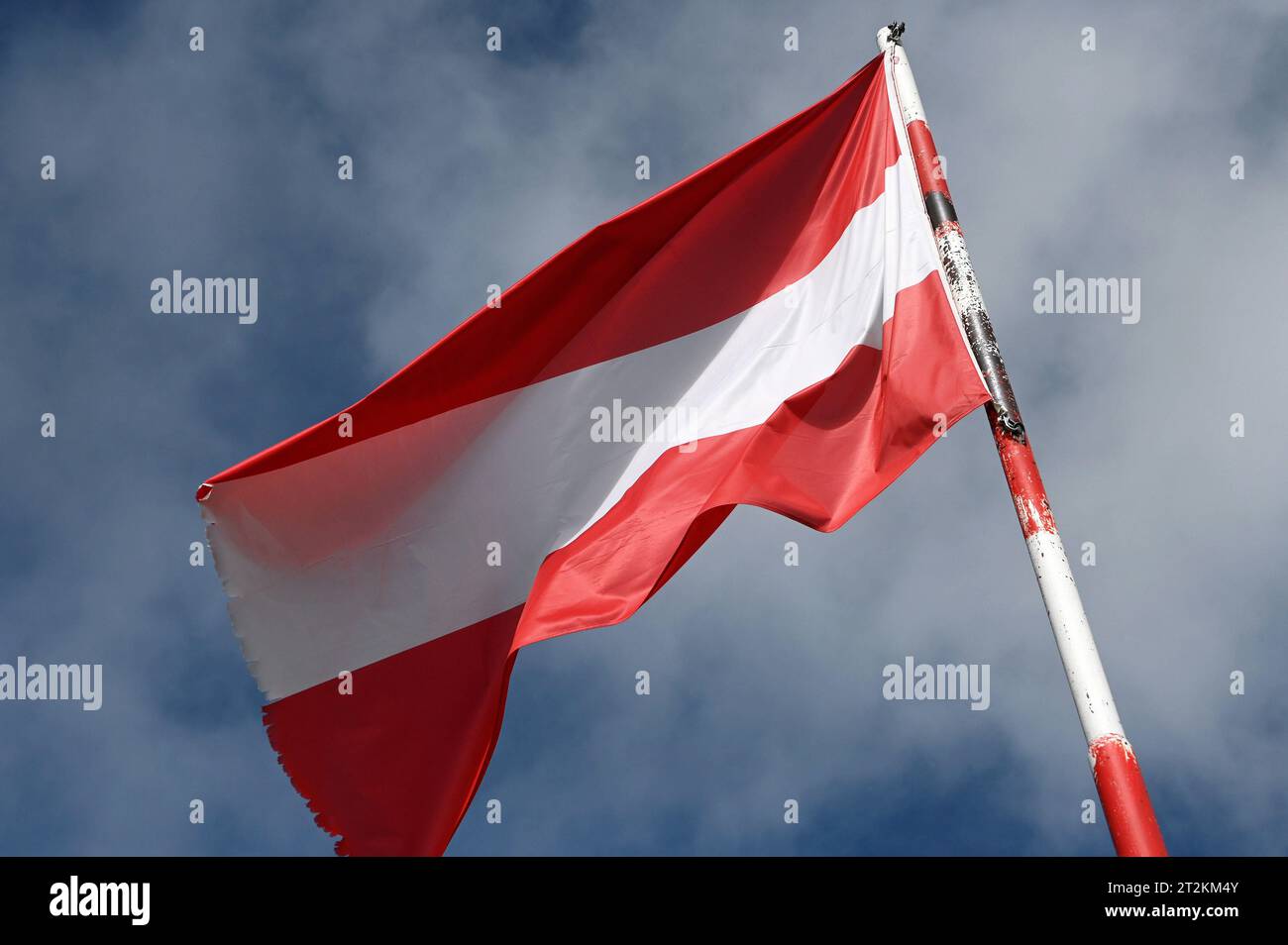 Die österreichische Fahne weht im Wind vor blauem Himmel. Flagge