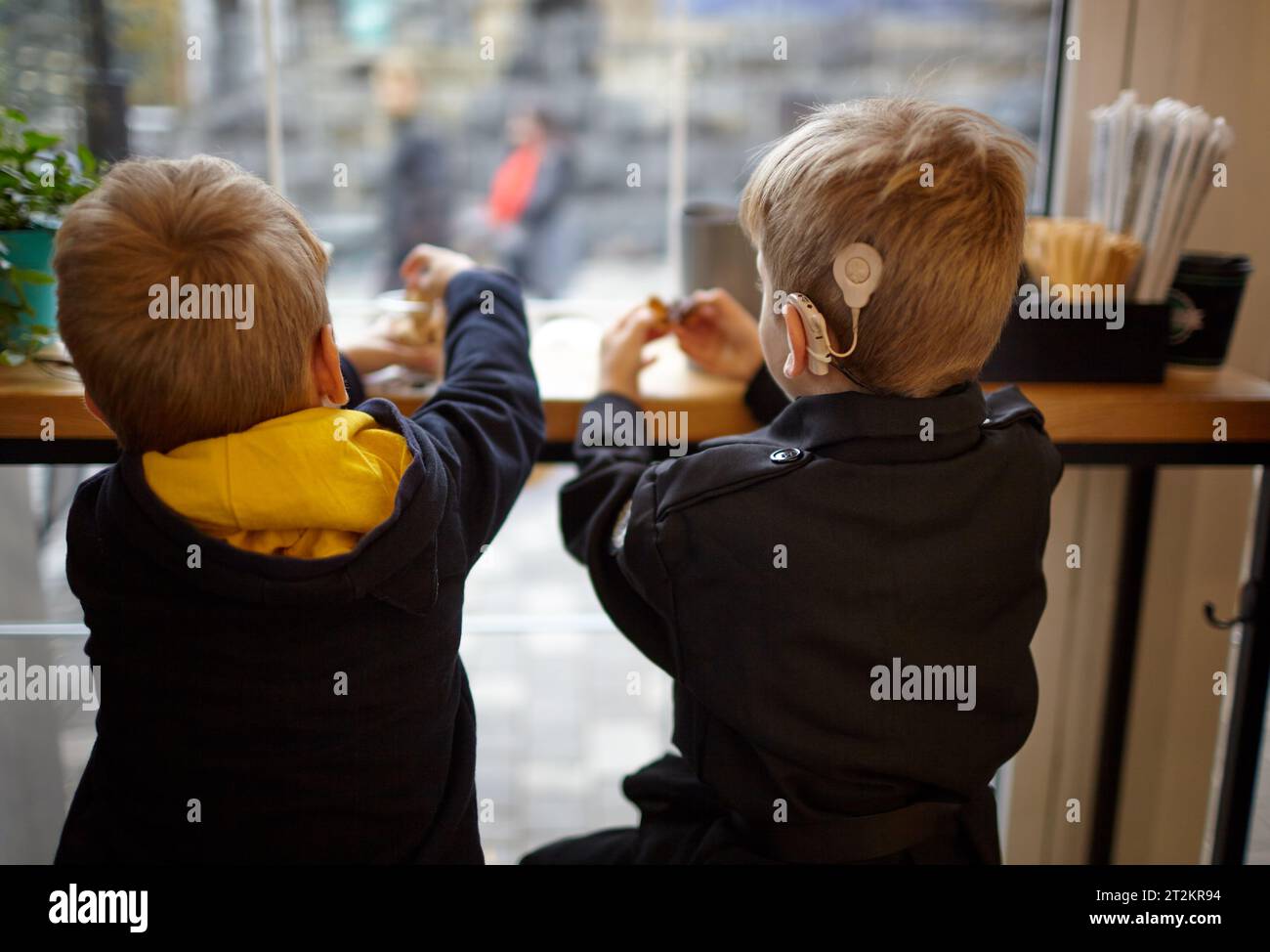 Boy have a Hearing Aids. Two twin brothers in a cafe. Selective focus, shallow depth of field Stock Photo