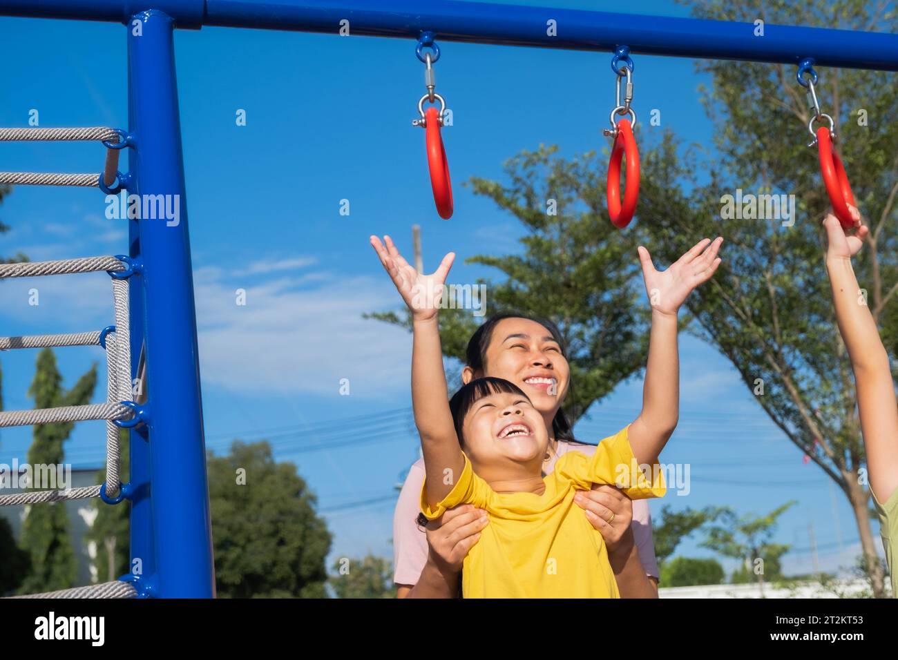 Cute little girl hanging bars in the playground. Happy little Asian