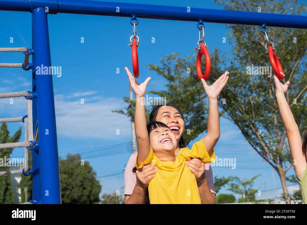 Cute little girl hanging bars in the playground. Happy little Asian child having fun on