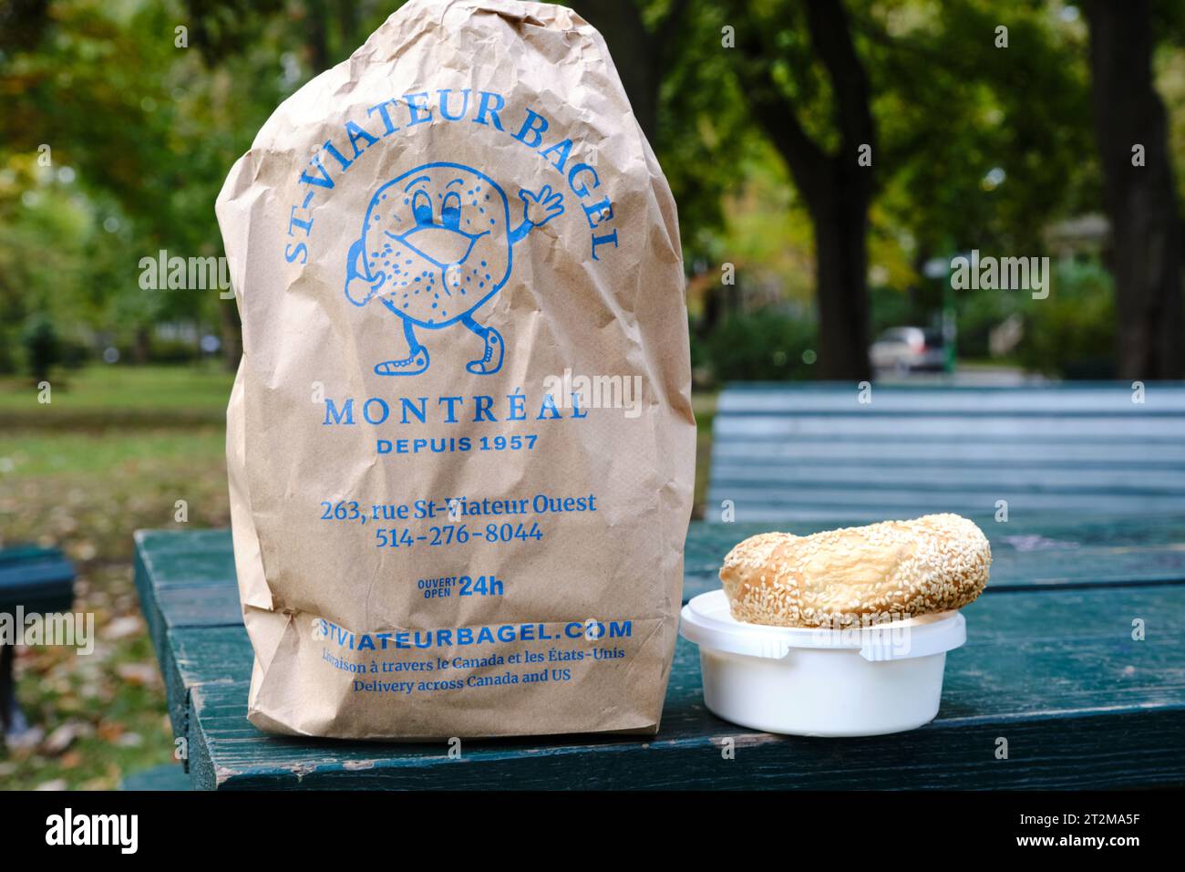 Paper bag of bagels from St-Viateur Bagel in montreal, with a bagel and creme cheese next to it out on a picnic table Stock Photo