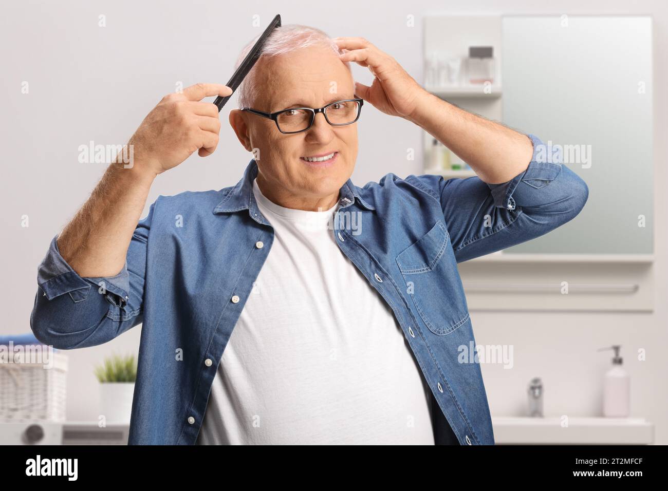 Cheerful mature man combing hair in a bathroom Stock Photo