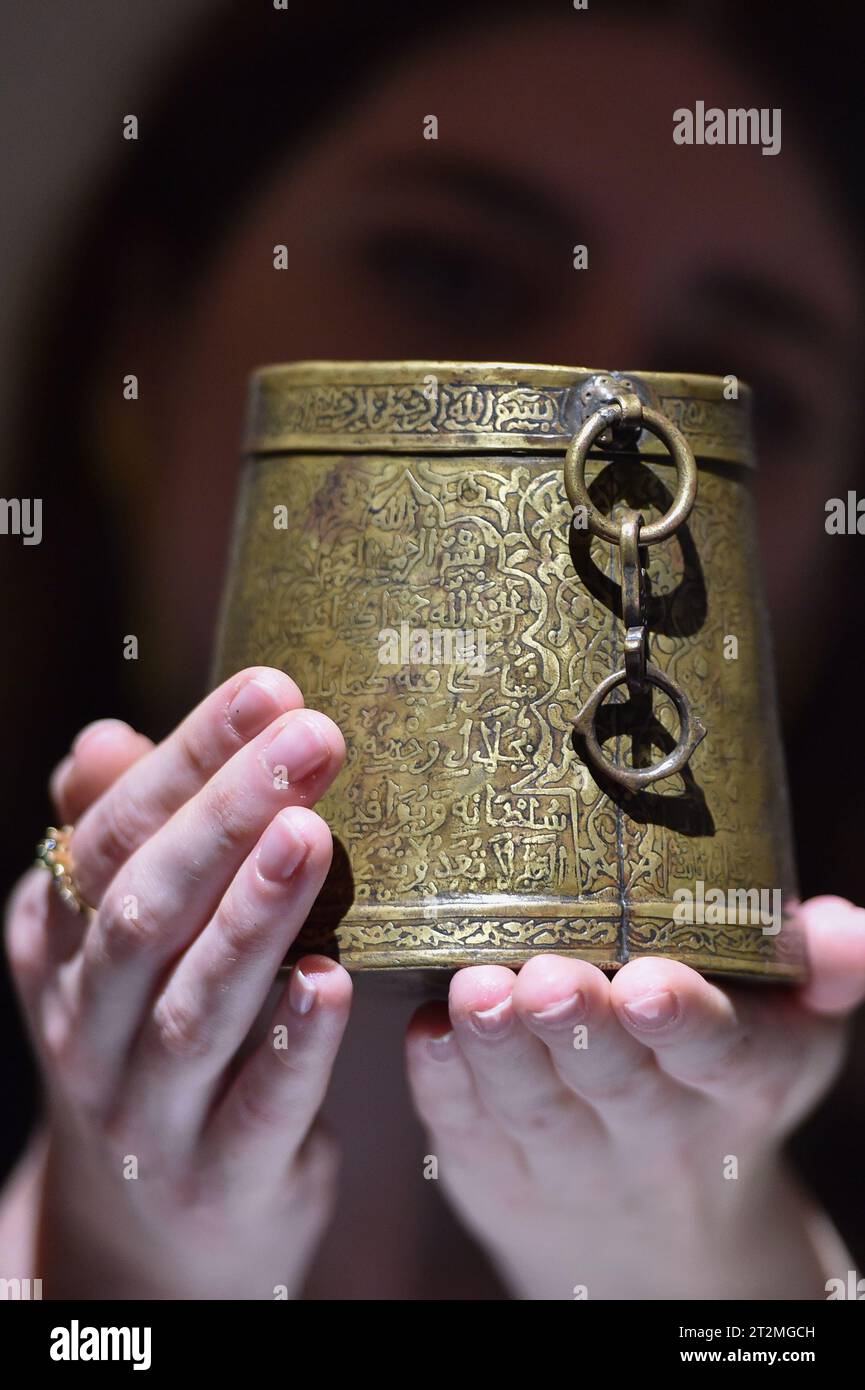 London, England, UK. 20th Oct, 2023. An inscribed bronze Zakat measure (mudd) ordered by Almohad Caliph Sultan Ya'qub al-Mansur ibn Yusuf in 1184 AD, originating from Spain or Morocco, with an estimated value of Â£150,000 - Â£250,000, is being presented by a technician at Sotheby's London. (Credit Image: © Thomas Krych/ZUMA Press Wire) EDITORIAL USAGE ONLY! Not for Commercial USAGE! Credit: ZUMA Press, Inc./Alamy Live News Stock Photo
