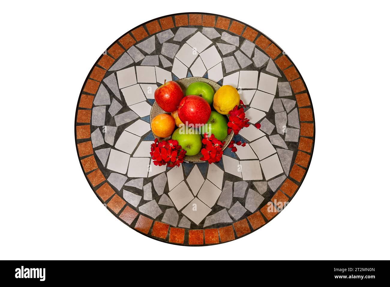 Bowl of fruit with red and green apples, lemons, and oranges on a mosaic tile table. Top view. Isolated on white background. Stock Photo