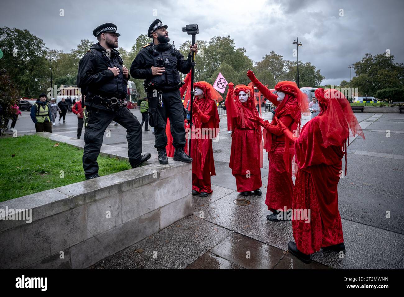 London, UK. 19th October, 2023. A police video surveillance unit is mocked by the Red Rebel Brigade during 'Oily Money Out' climate protest. Activists from Fossil Free London gather before marching from Marble Arch to the Intercontinental Hotel Park Lane to demand changes to the fossil fuel industry. A three day Energy Intelligence Forum (previously the Oil and Money Conference) is currently being held at the Intercontinental Hotel Park Lane, outside which protests have been taking place for this week. Credit: Guy Corbishley/Alamy Live News Stock Photo